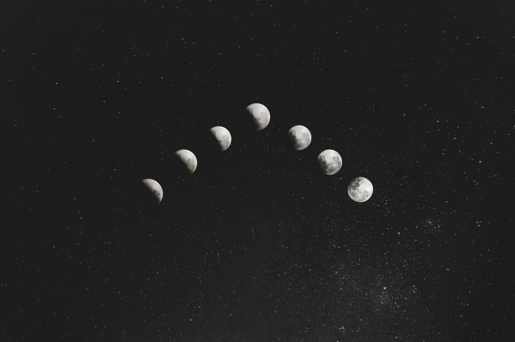 Phases of the moon arcing across a starry night sky