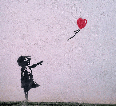 Street-art stencil of a girl letting go of a red heart-shaped balloon