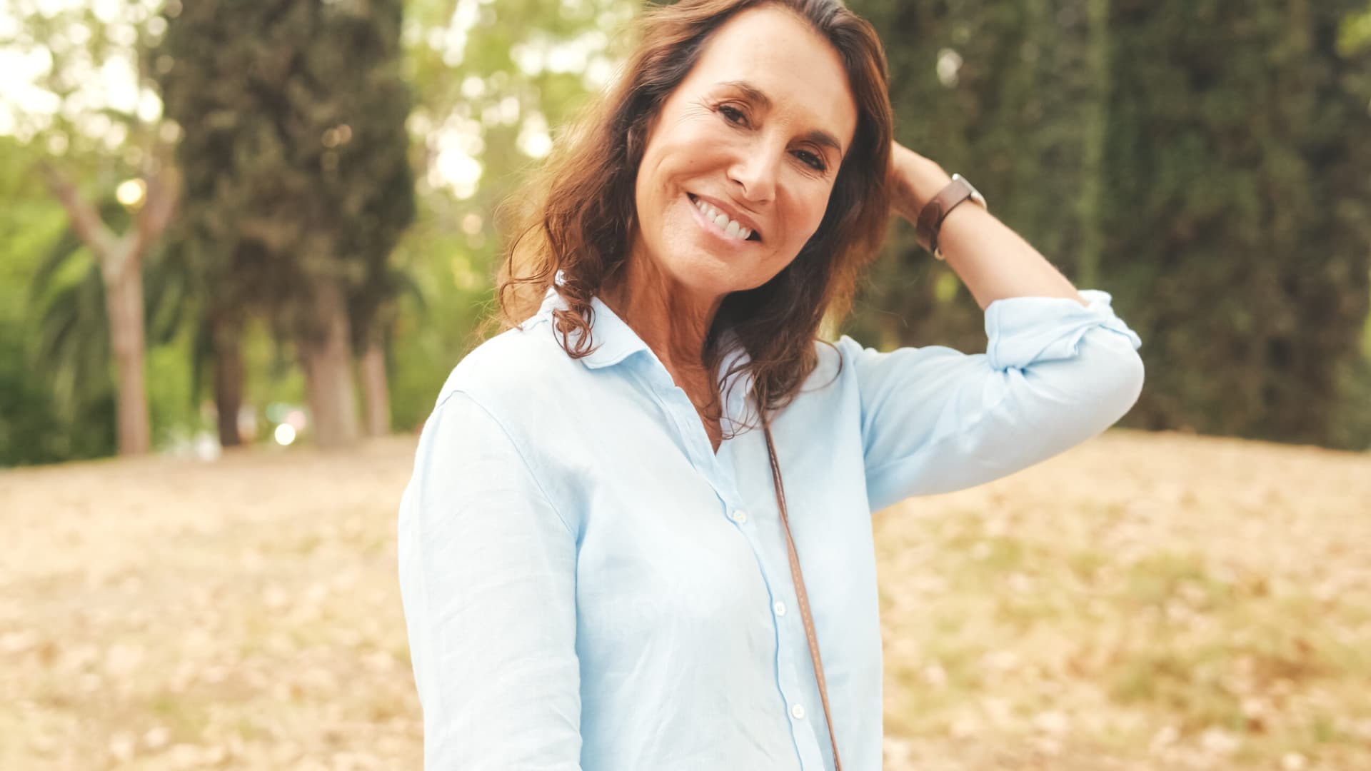 Close-up of a woman smiling warmly outdoors.