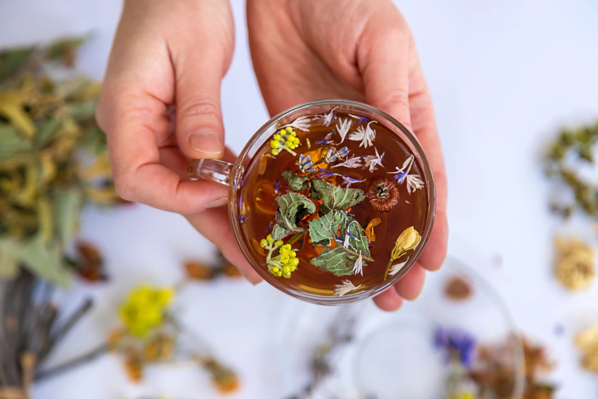 Herbal tea with medicinal herbs and flowers on a table.