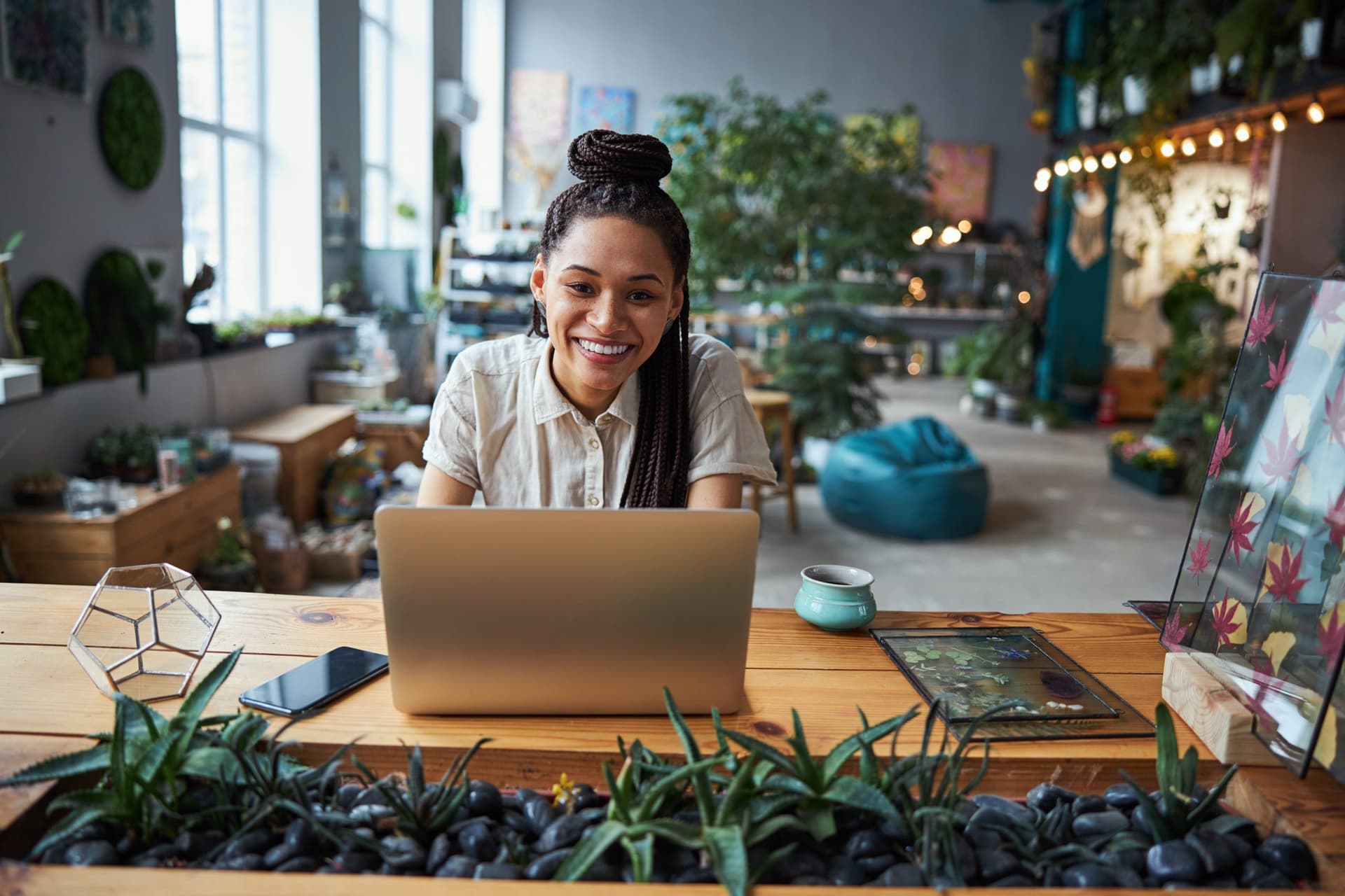 Woman sitting at a laptop with flowers nearby.