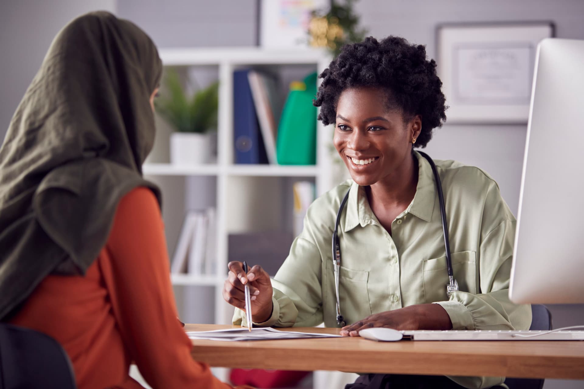 Doctor smiling while reviewing lab results with a patient at her desk.