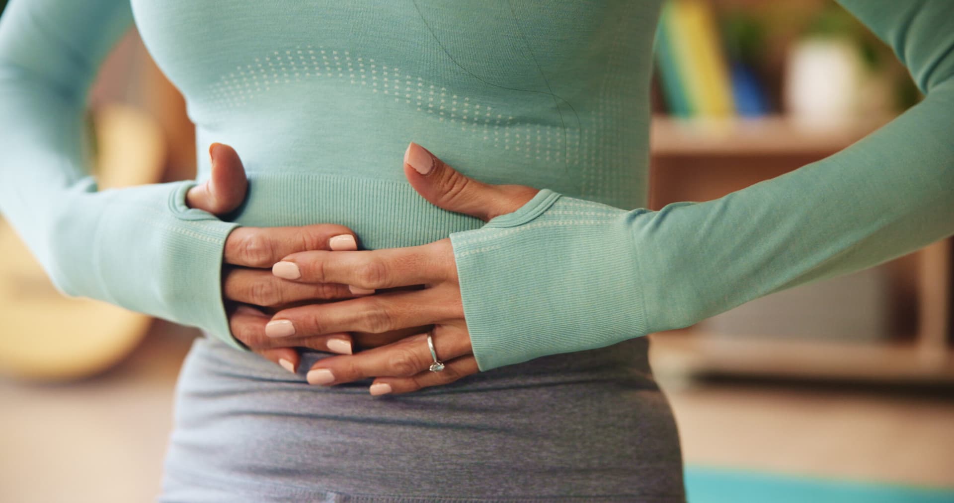 Woman on a couch holding her stomach in discomfort.