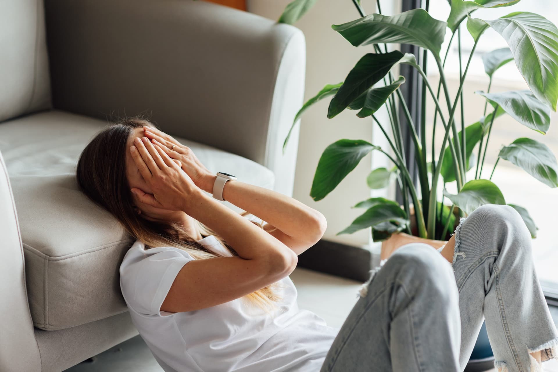 Young woman sitting at home, weighed down by anxious thoughts.