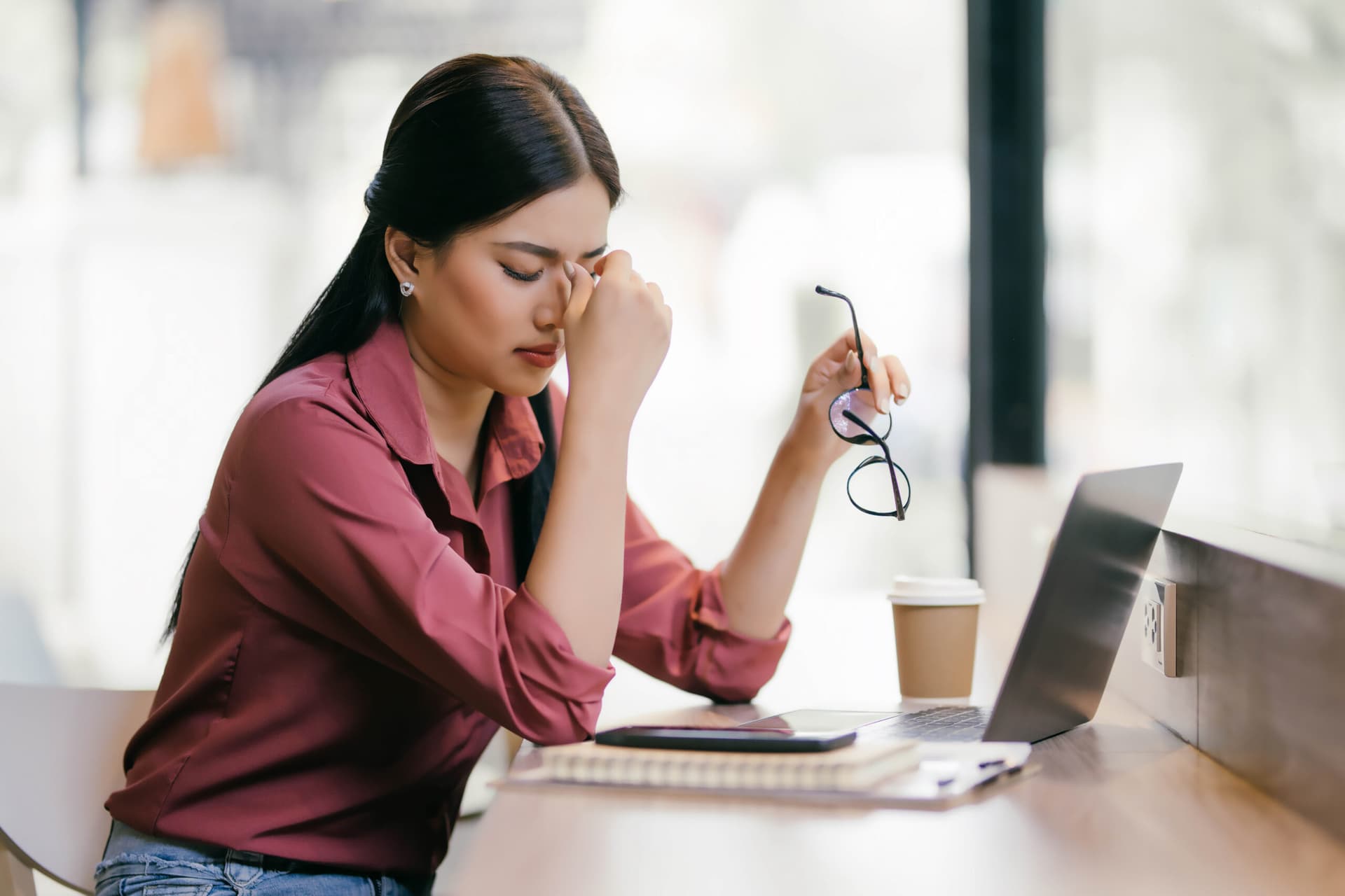 A woman is sitting at a desk with a laptop and a notebook