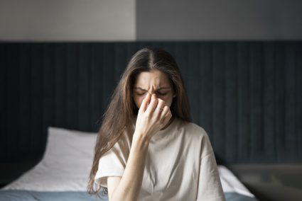 Person holding their head in discomfort, showing signs of headache or illness possibly linked to mold exposure